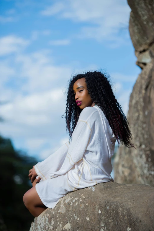 the young woman is sitting on a rock