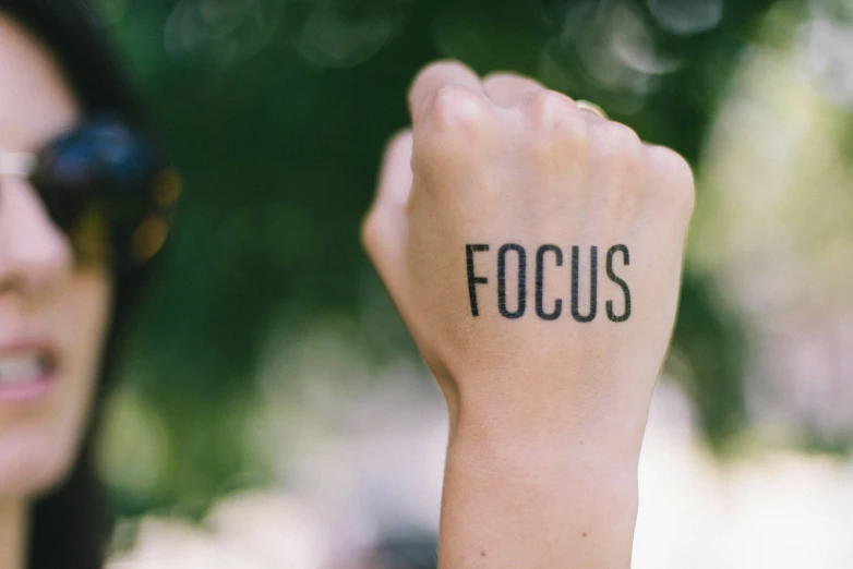 the word focus spelled by black lettering on a women's hand