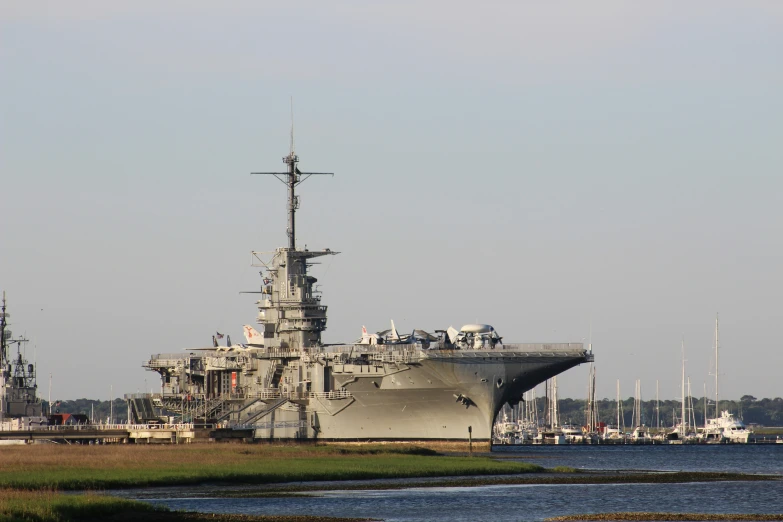 a military ship is docked with a smaller boat in the water nearby