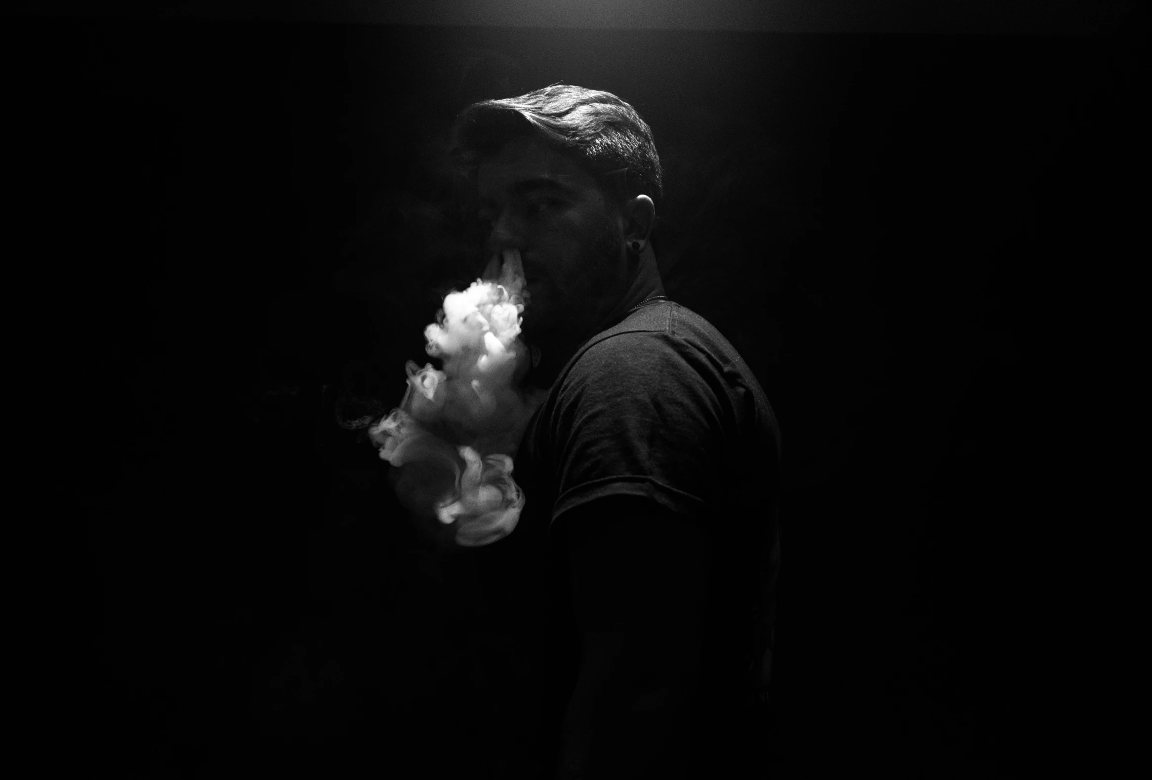 the silhouette of a man smoking a cigarette in the dark