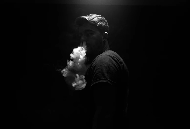 the silhouette of a man smoking a cigarette in the dark