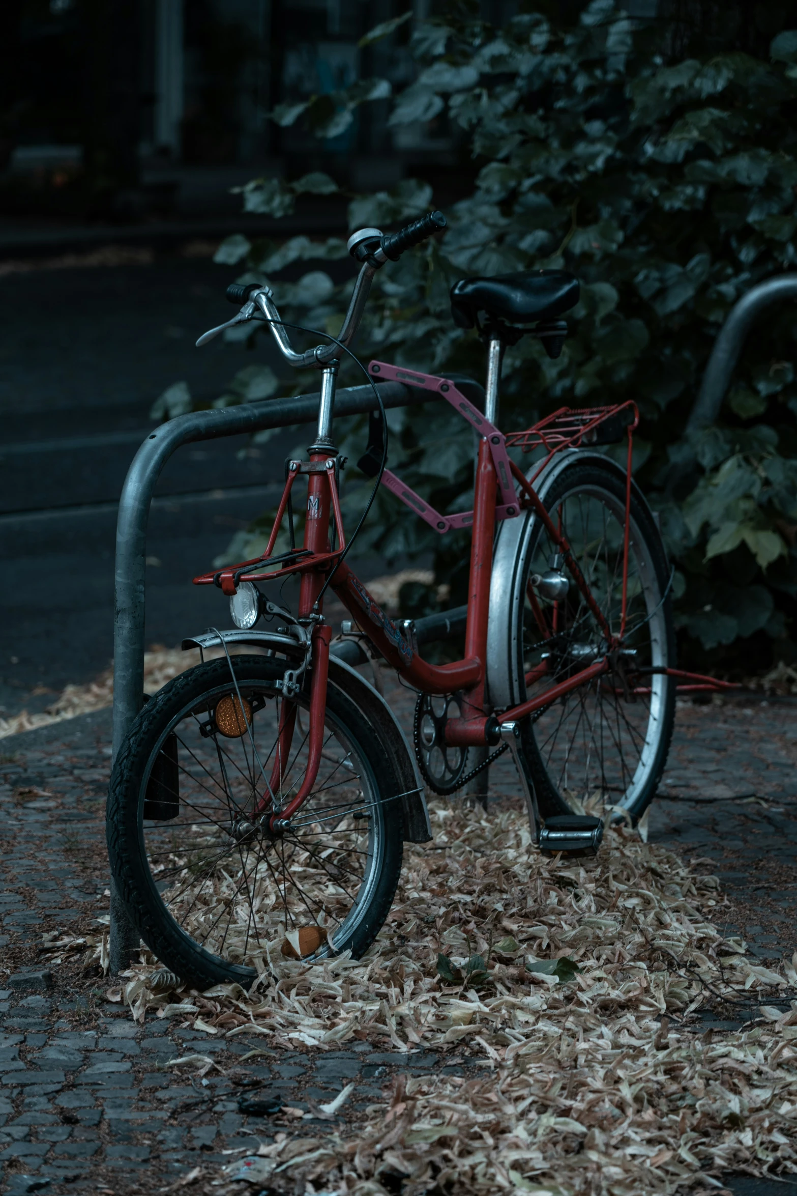 an old red bike with a bar and front basket is parked outside