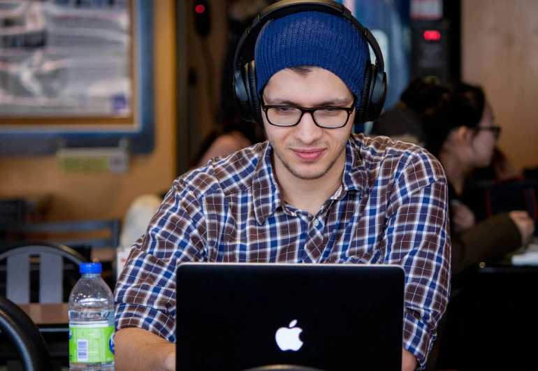 a young man wearing headphones using a laptop