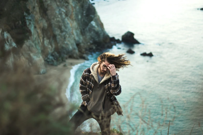 young man with long hair walking near the ocean