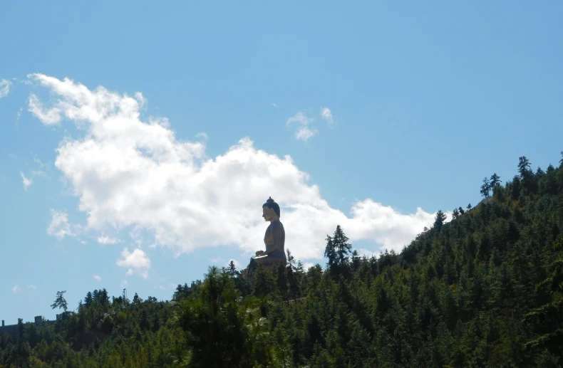 a statue of buddha sitting on top of a mountain