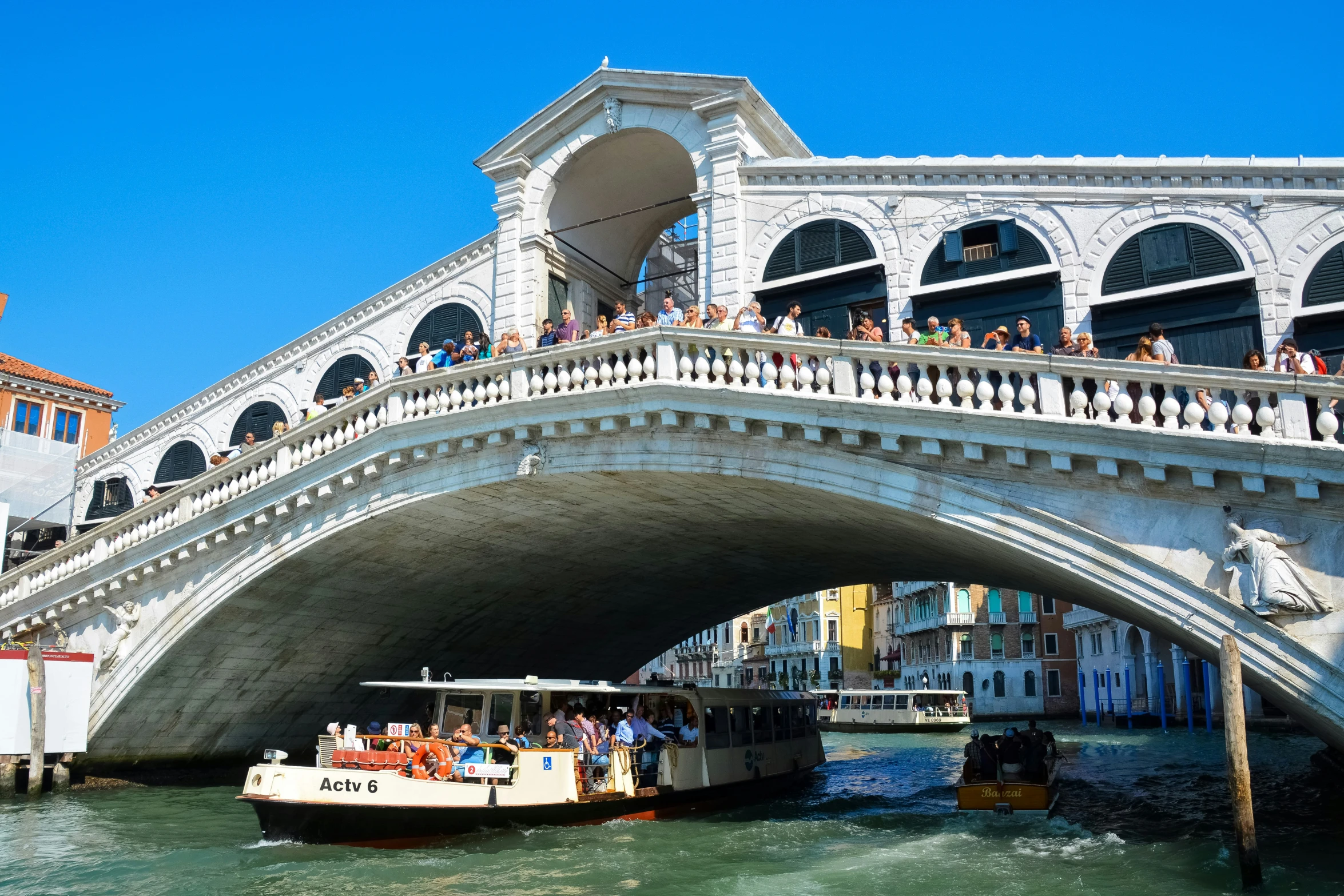 a group of people riding on top of a boat under a bridge