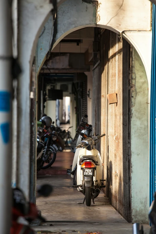 a parked scooter sitting in an arch with motorcycles lined around