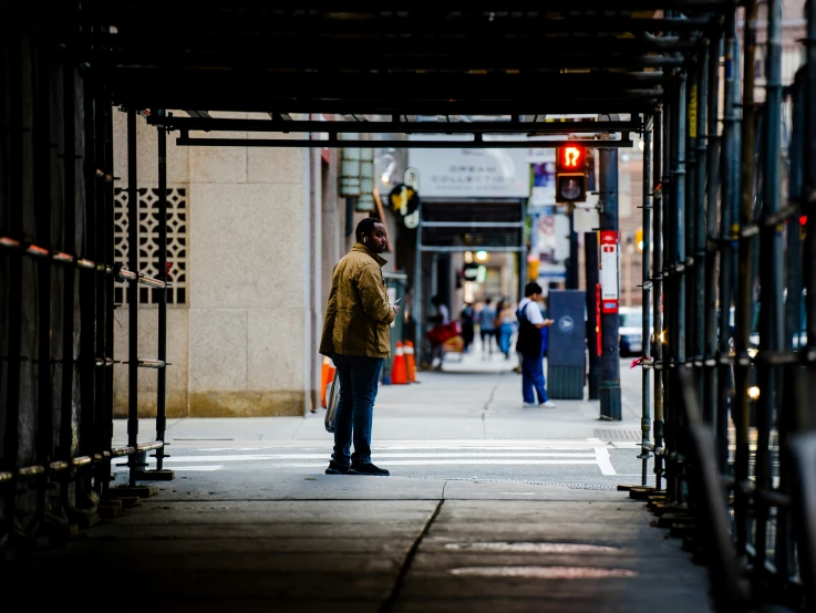 a person stands alone on the sidewalk waiting to cross