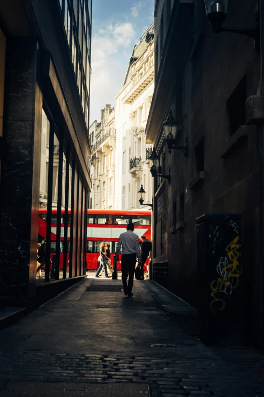 a man standing on an alleyway holding a red umbrella