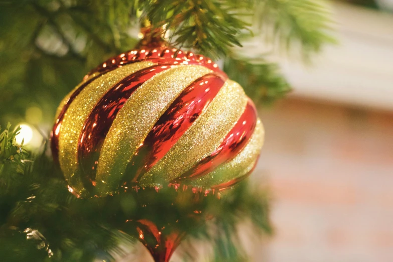 a red and yellow christmas ornament hanging from a christmas tree