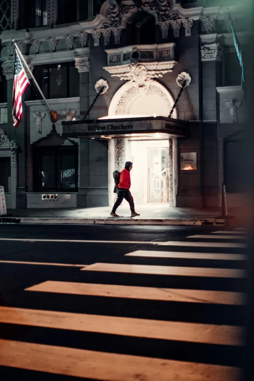 a person walking across a street with the city building in the background