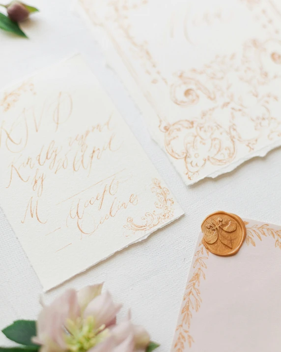 a table topped with different types of white and gold wedding paper