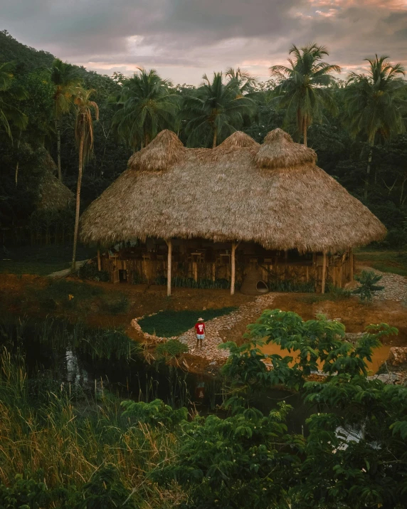 a large native village in front of trees and water