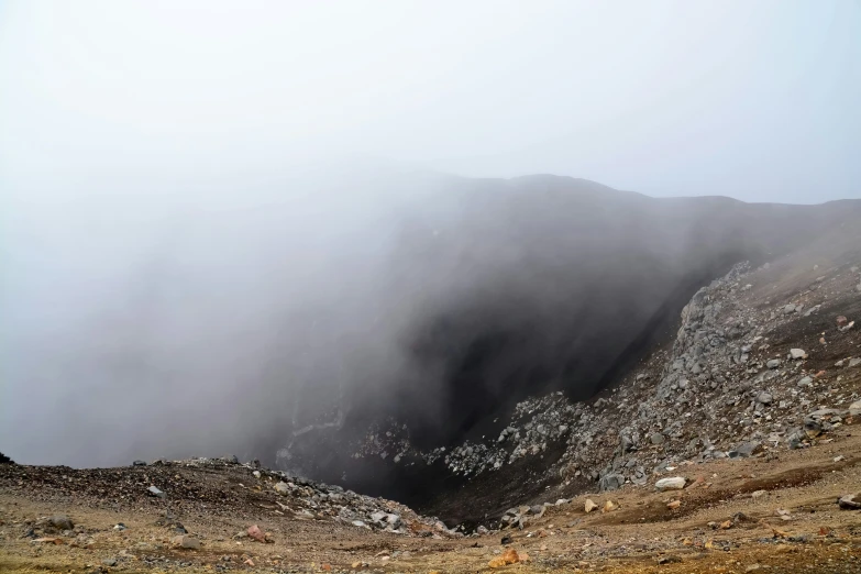 a large grassy hillside with fog and low lying clouds