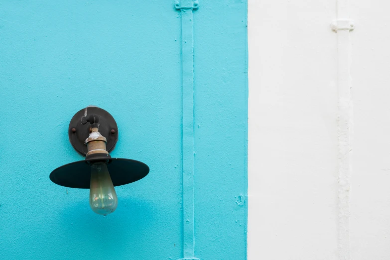 a small light hanging on the side of a blue wall