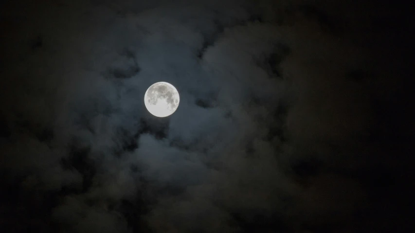 a large moon in the dark sky and some clouds