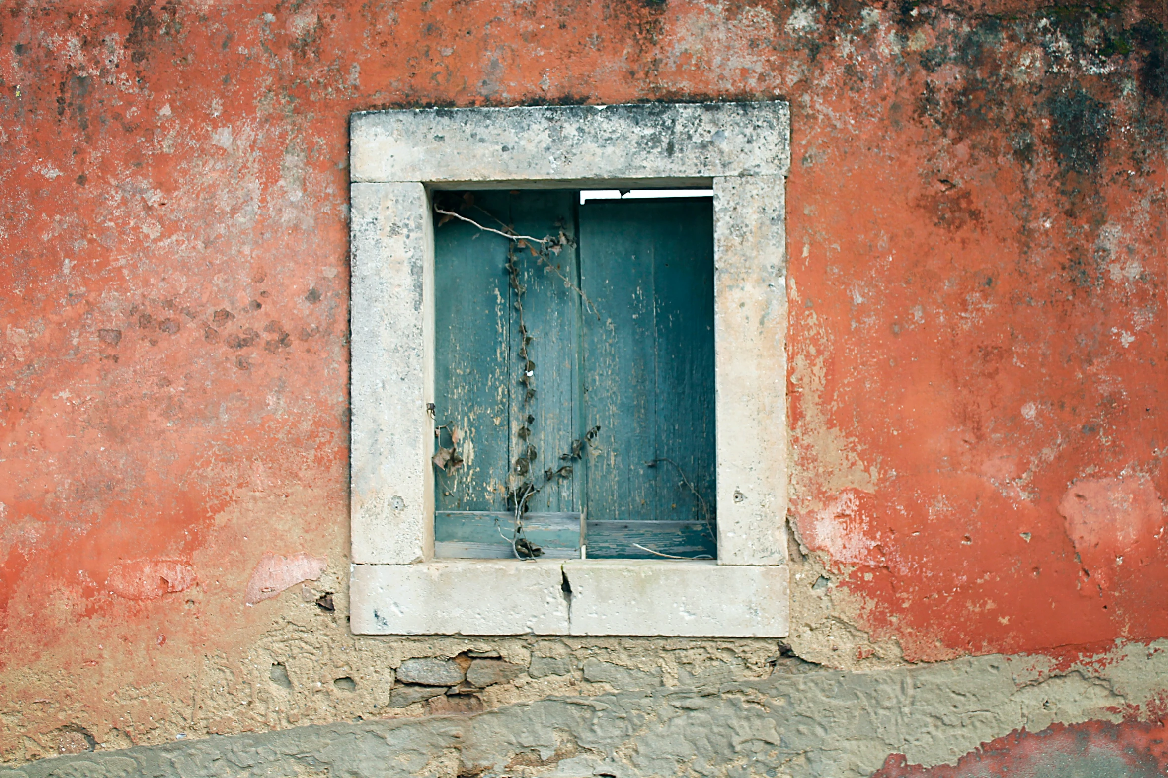 a dirty building wall has a broken window