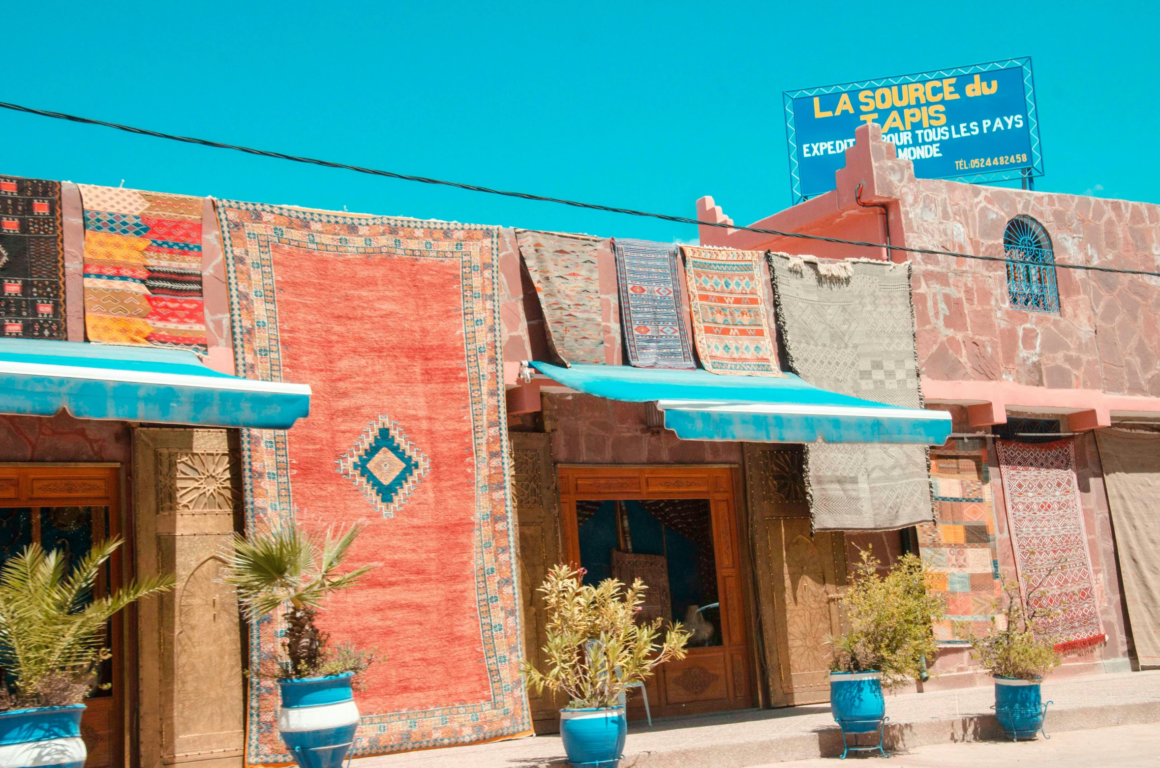 the outside of a colorful building with blue and red awnings