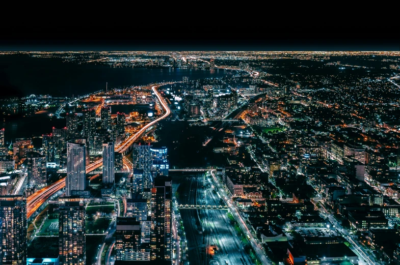 a nighttime view of a city, including a bridge, city lights, buildings and some other lights