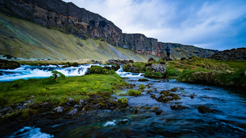 a man in a black jacket is standing near a river