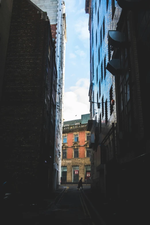 a narrow alley way in a city with a building and man on either side