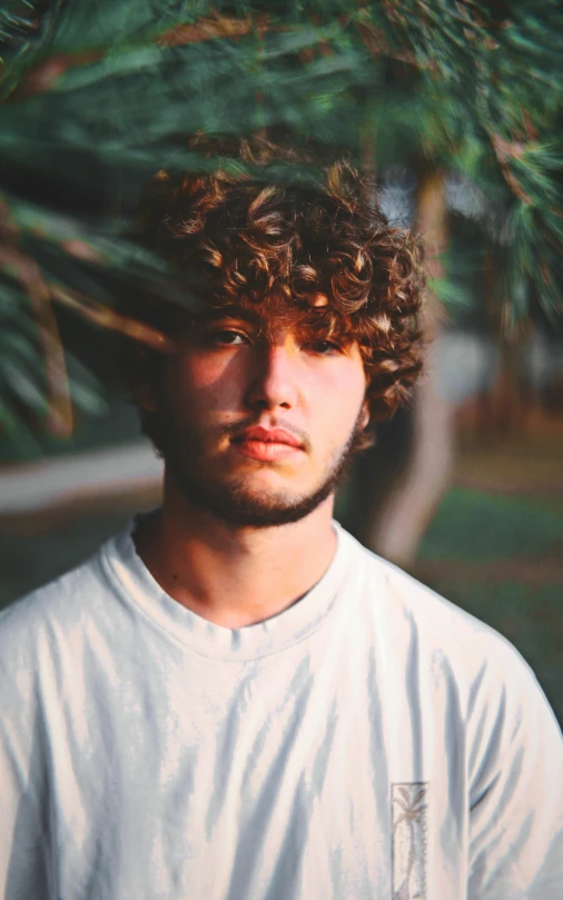 the man is wearing a white t shirt and has curly hair