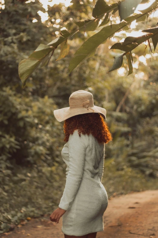 woman in hat walking in the forest wearing grey dress