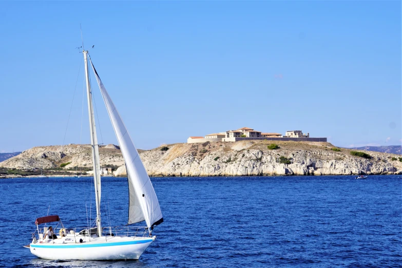 a sail boat in the ocean near an island