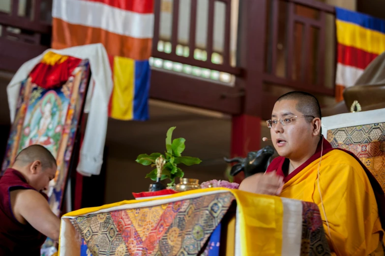 a man speaking at an event in front of flags