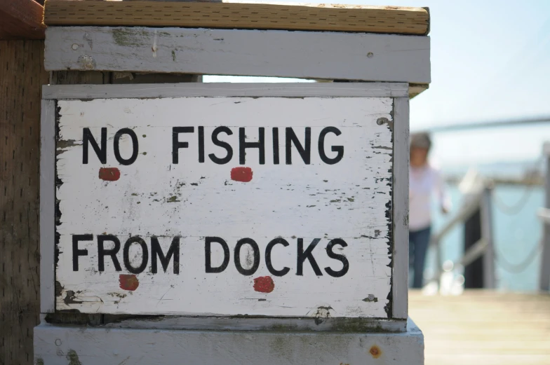 a wooden sign warning of fishing from docks