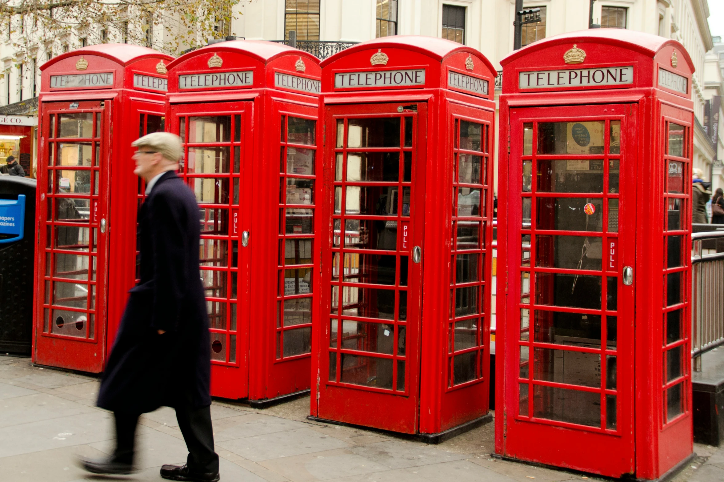 a woman walking past red telephone booths