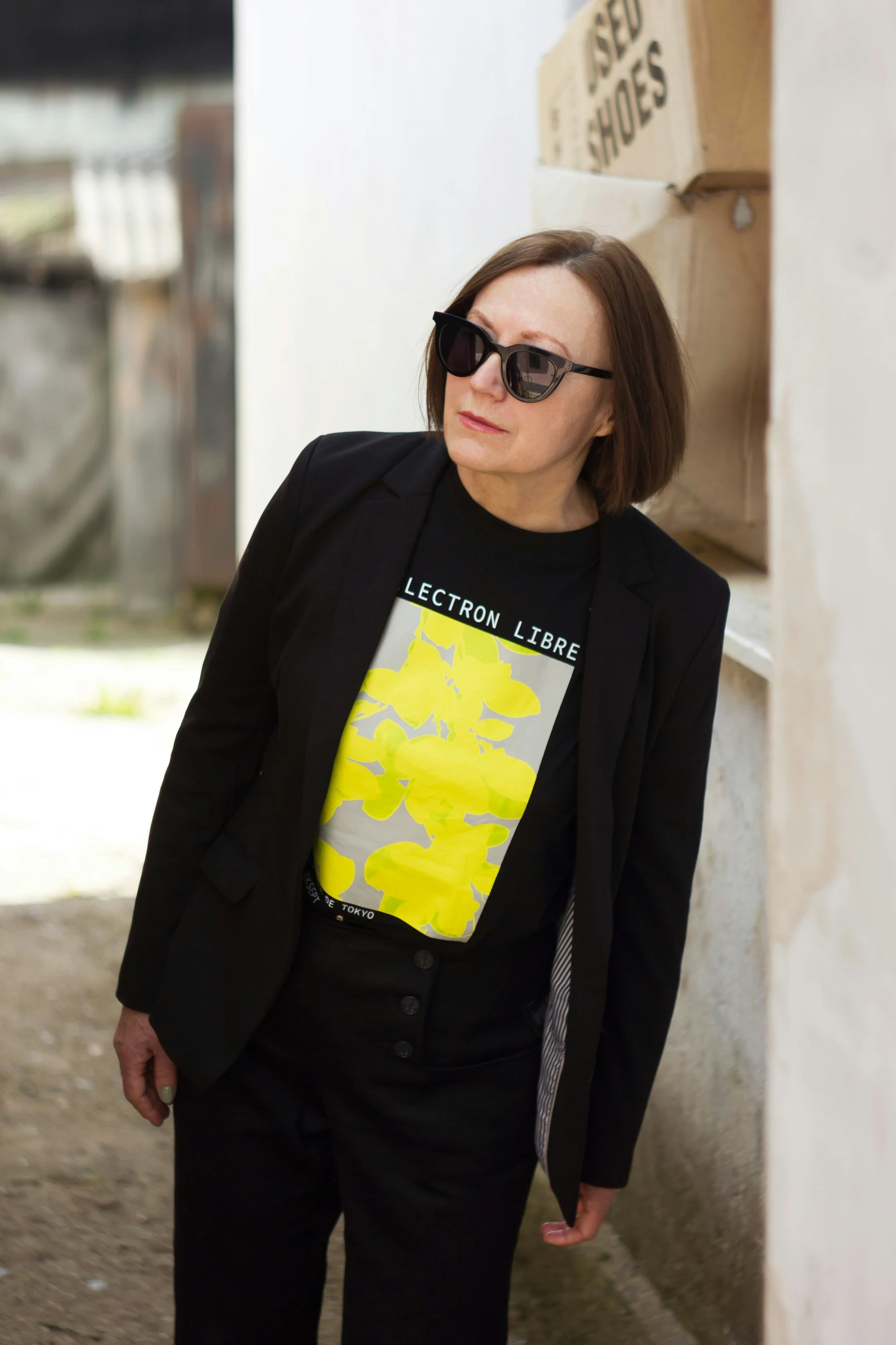 a woman standing on the side walk with sunglasses