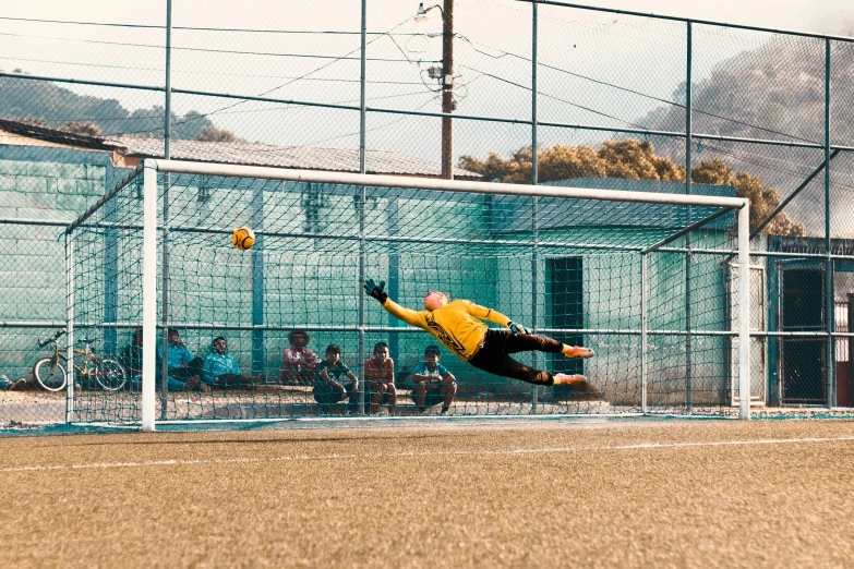 man catching ball with right leg while he goes to catch it