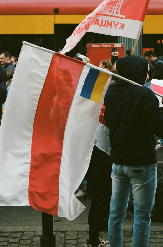 a man standing next to a crowd holding a flag