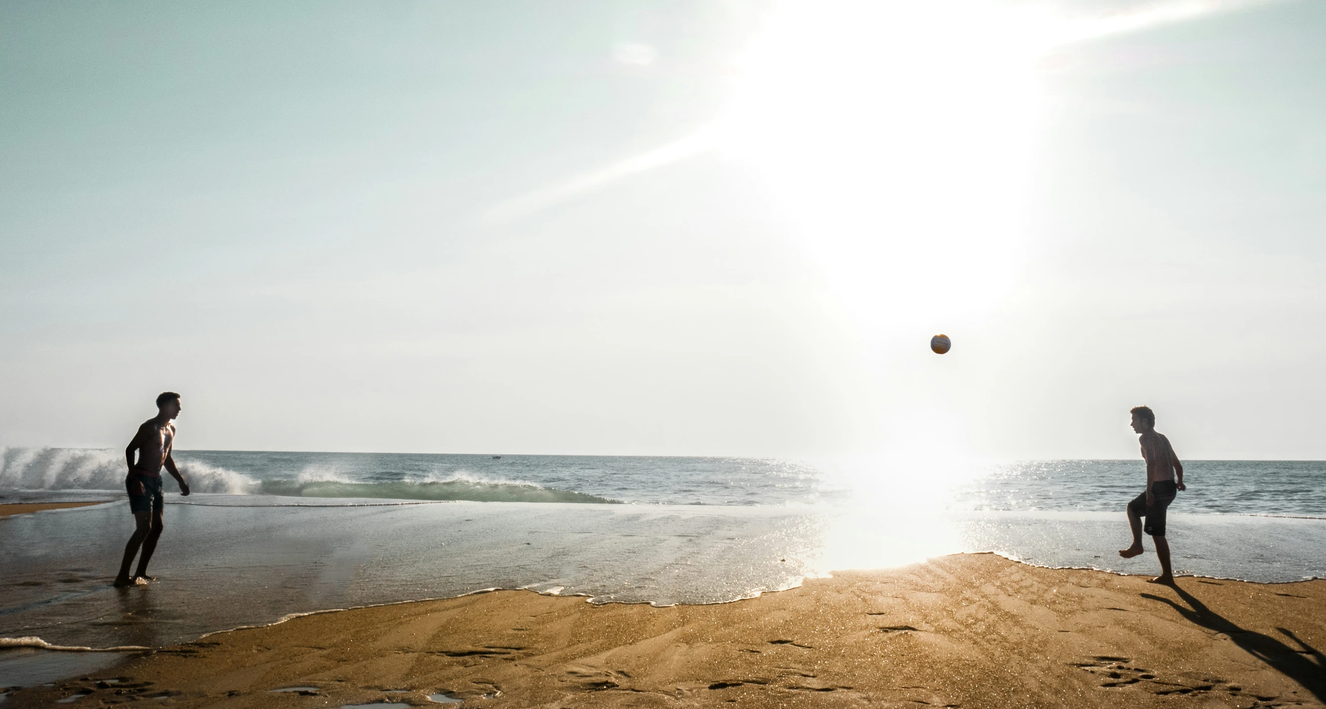 a couple of men standing on a beach near the ocean