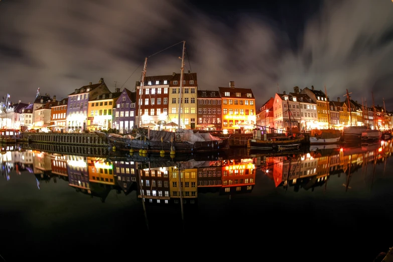 the cityscape is lit up at night, along with the boats