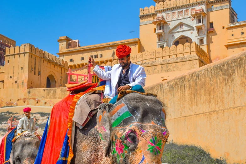 the man in a turban riding an elephant at an ornately decorated building