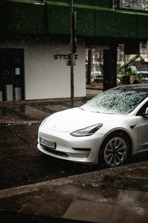 a white car with its hood up driving in the rain