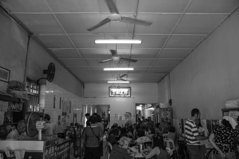 a group of people stand at tables in a small restaurant