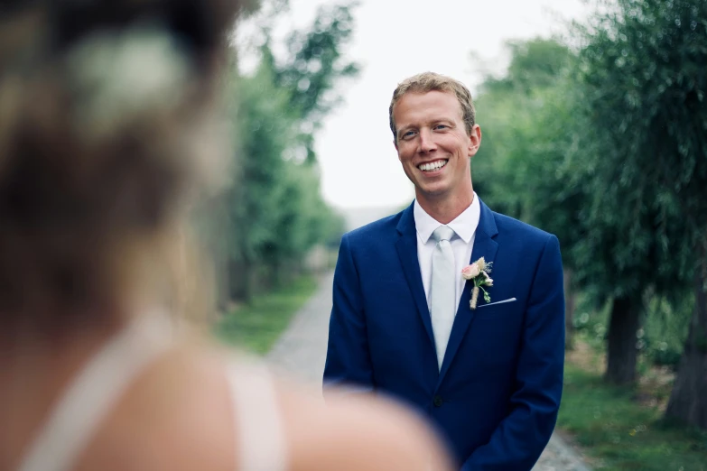 man in blue blazer standing beside a road