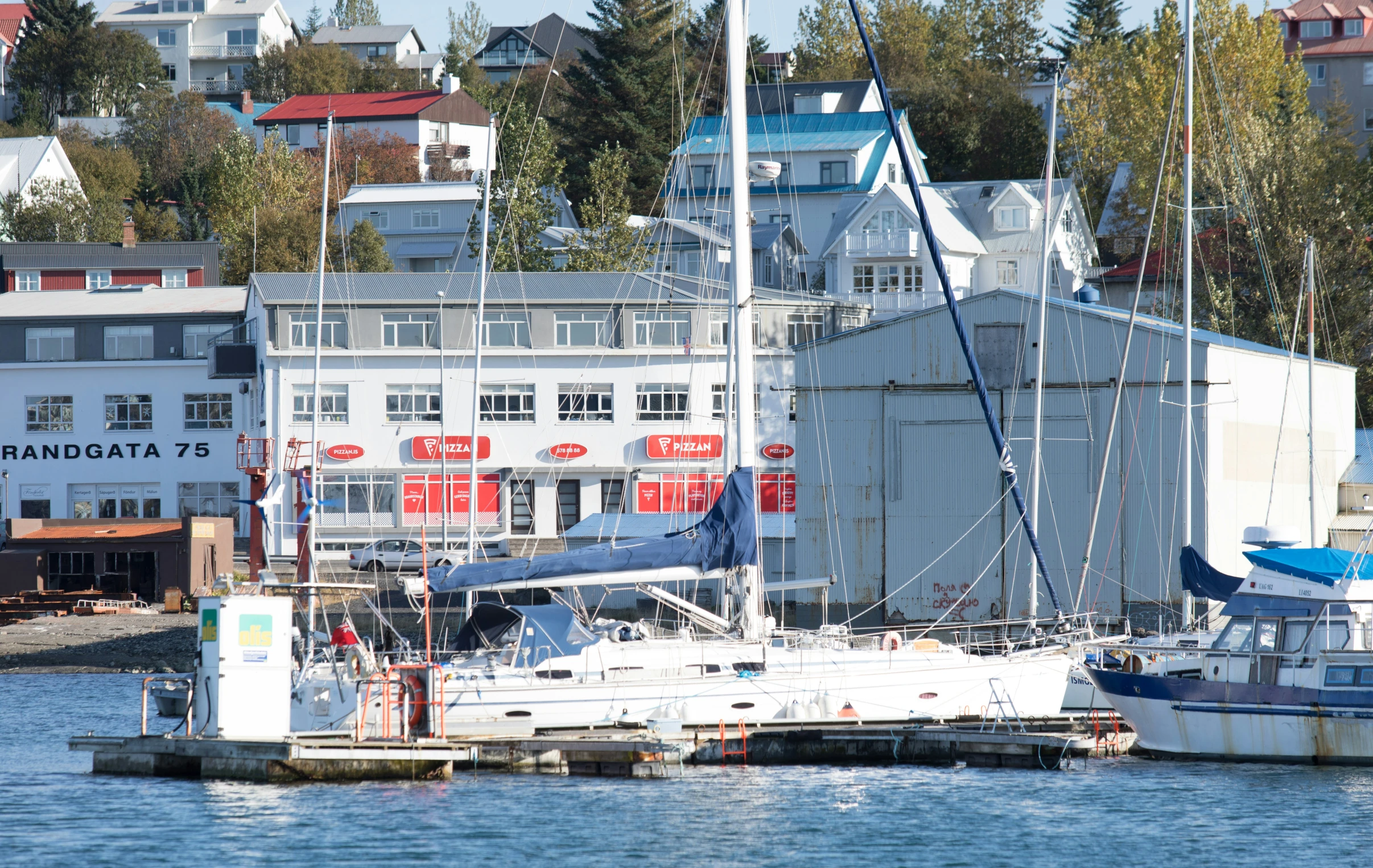 a few boats docked at a marina near an urban area