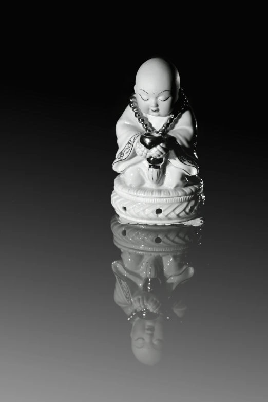 a white buddha statue on top of a table next to a mirror