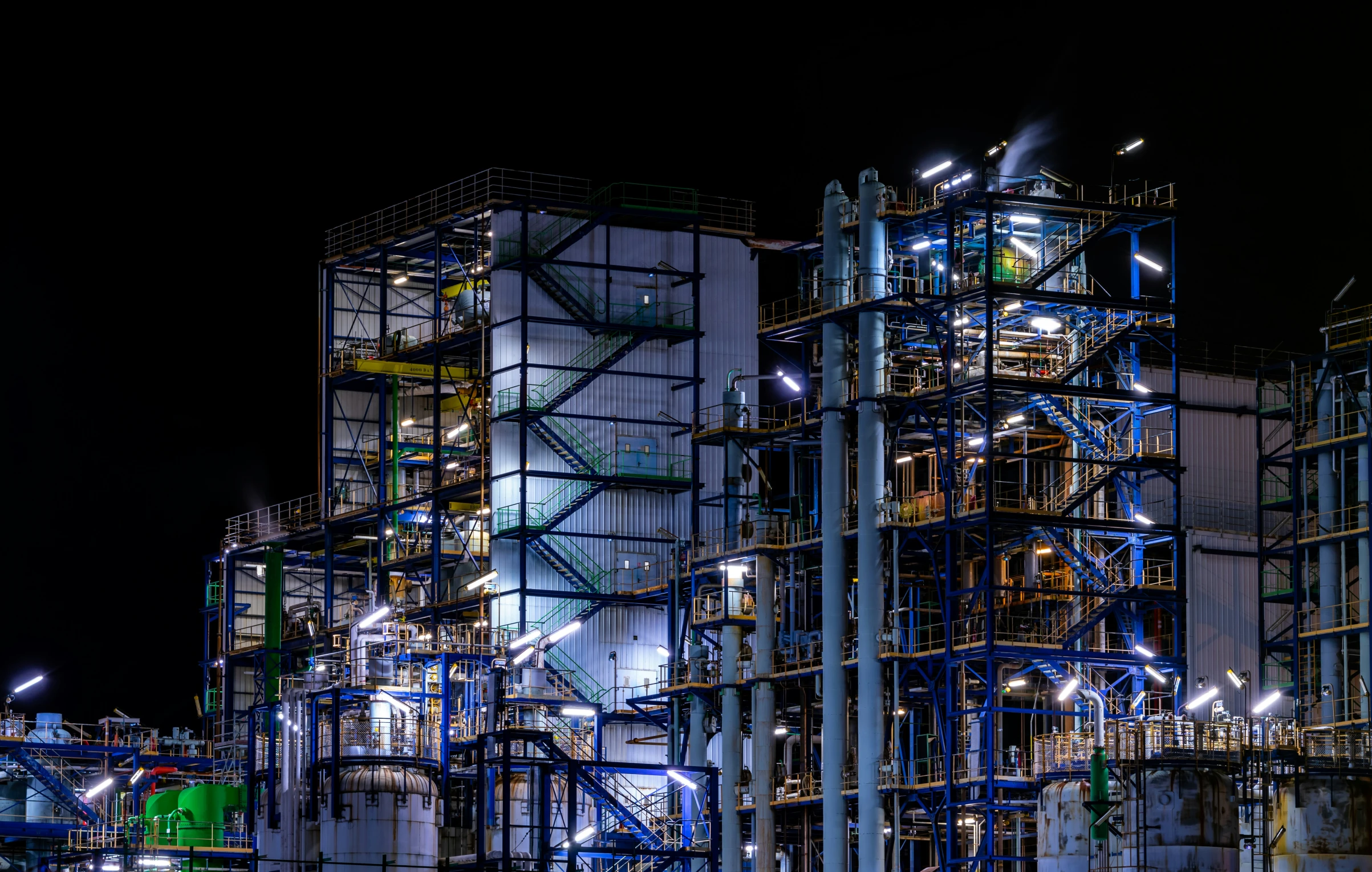 an industrial pipe structure at night lit by street lamps