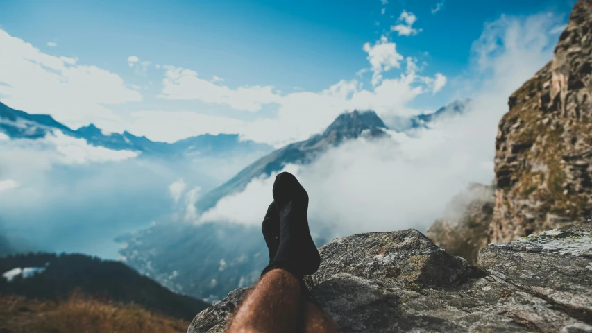 a person is standing on top of the mountain with their feet in the air