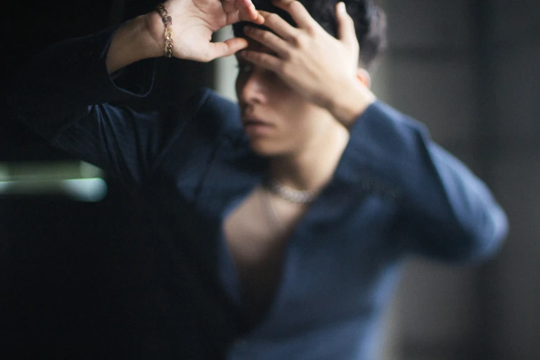 a woman in blue top looking into a mirror