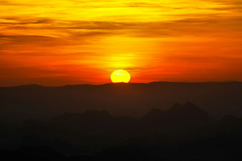 the sun setting over mountains and land with a hazy sky