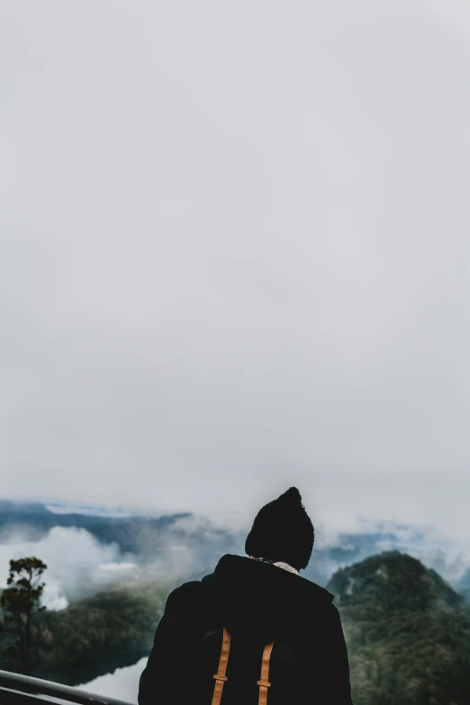 man in hoodie looking over mountain during daytime