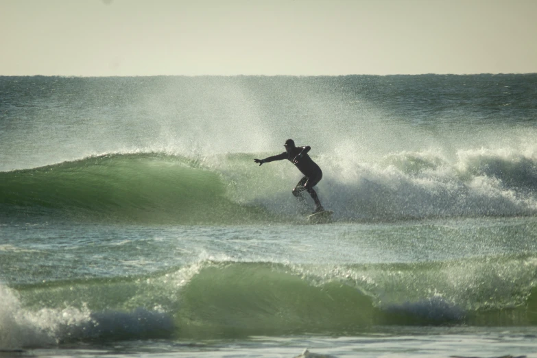 a surfer in a wetsuit riding the crest of a wave