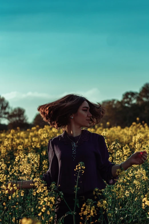 woman standing in middle of yellow flower field