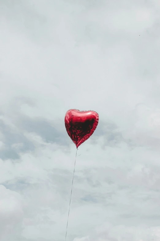 a heart shaped balloon flies through the sky